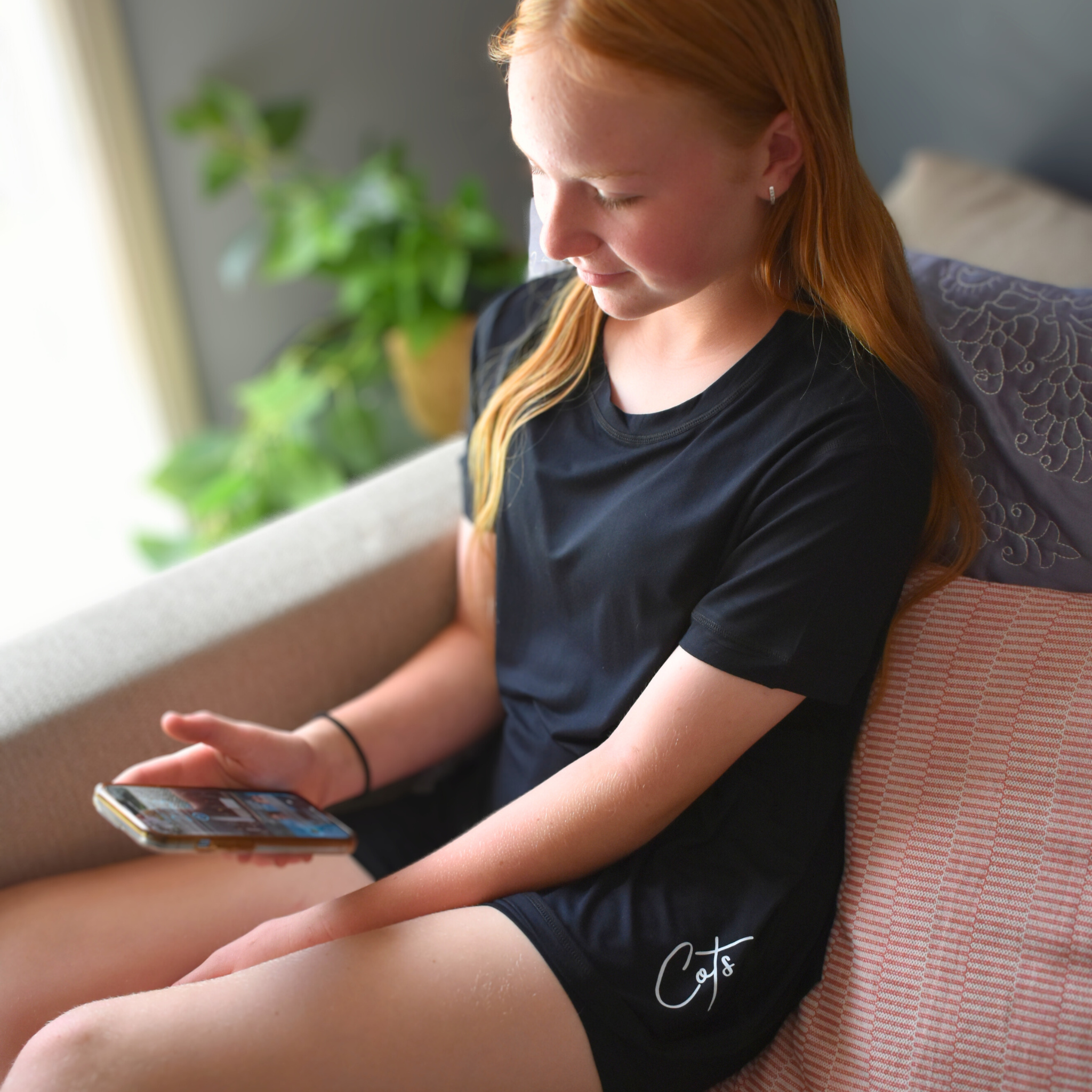 A sitting girl wearing midnight short set - - pajama short set - from Comfort on the Spectrum.