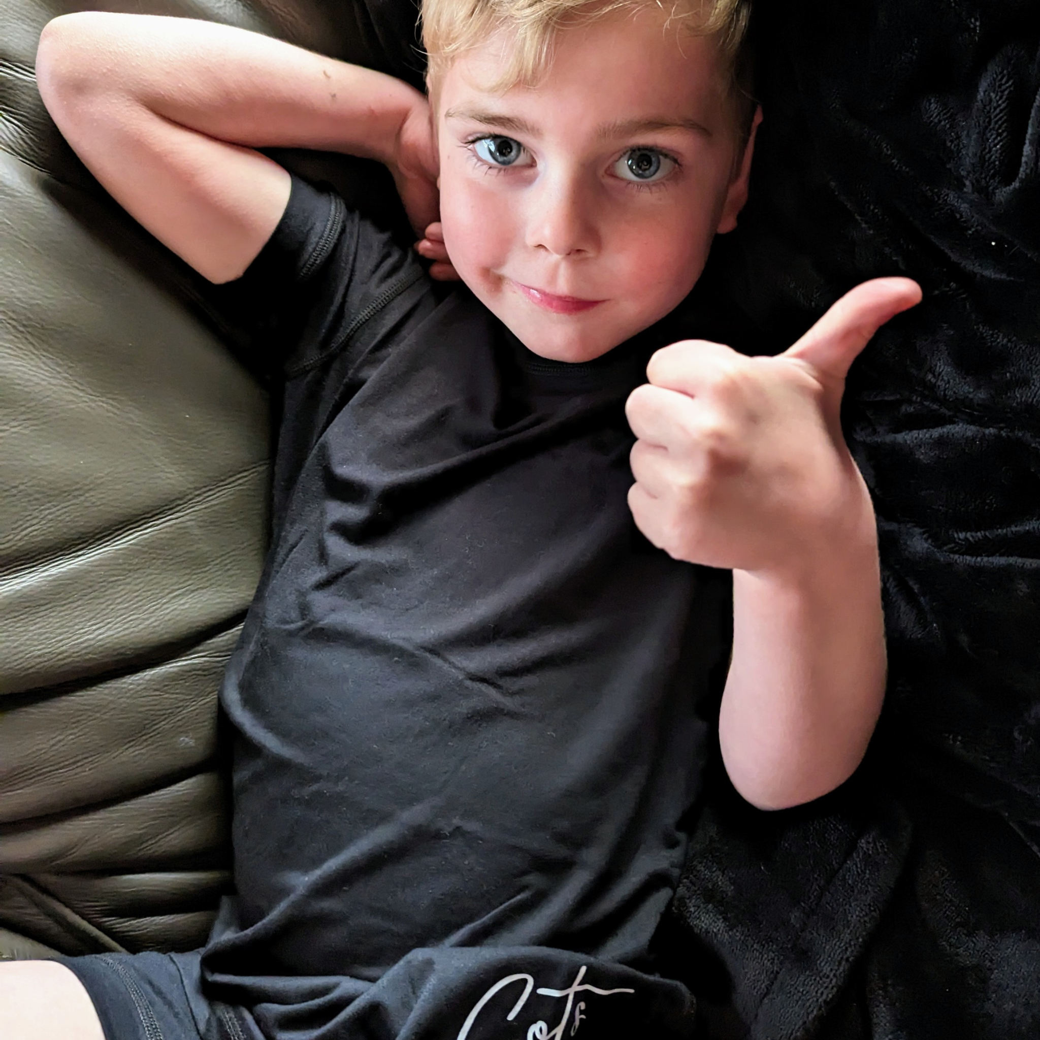 A boy wearing the midnight short set - pajama short set - from Comfort on the Spectrum.