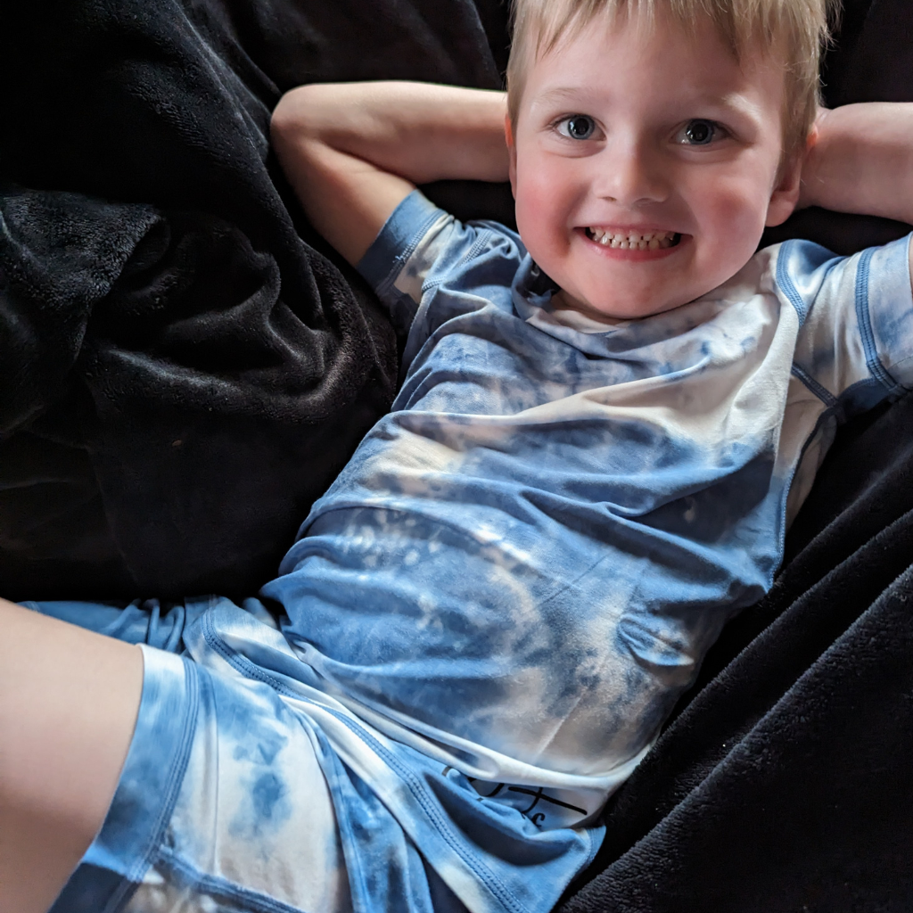 A smiling boy wearing sea breeze pj short set from Comfort on the Spectrum.