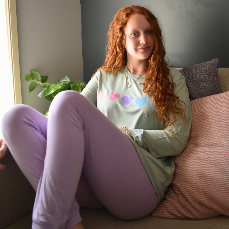 A sitting girl wearing a lavender sweetheart long set pajamas for teens and kids from Comfort on the Spectrum.
