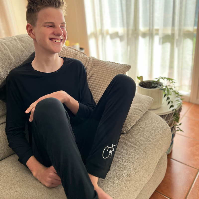 A smiling boy wearing the midnight long set - pajama set for teens - from Comfort on the Spectrum.