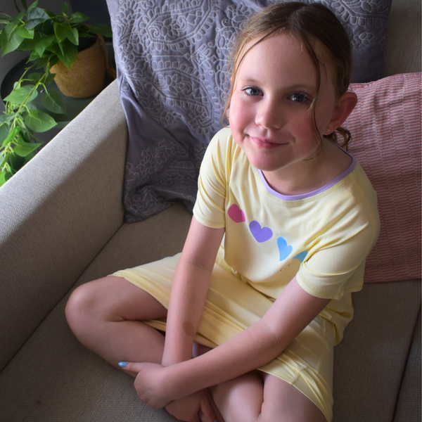 A sitting girl wearing lemon loveheart nightdress - nightdresses for women and kids - from Comfort on the Spectrum.