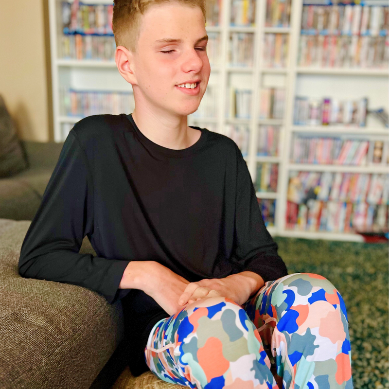 A sitting boy wearing camo  Long Set Pajamas for Teens & Kids from Comfort on the Spectrum.