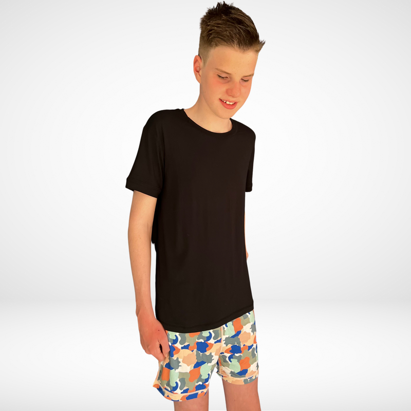 Smiling boy wearing the camo short set- pajama short set from Comfort on the Spectrum.