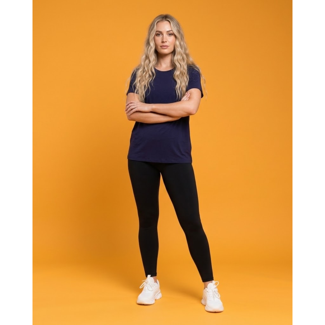 Woman wearing a navy t-shirt and black leggings on an orange background