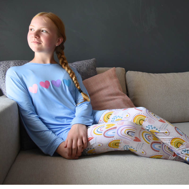 seated girl wearing rainbow sweatheart - pajama set for teens / long set from comfort on the spectrum
