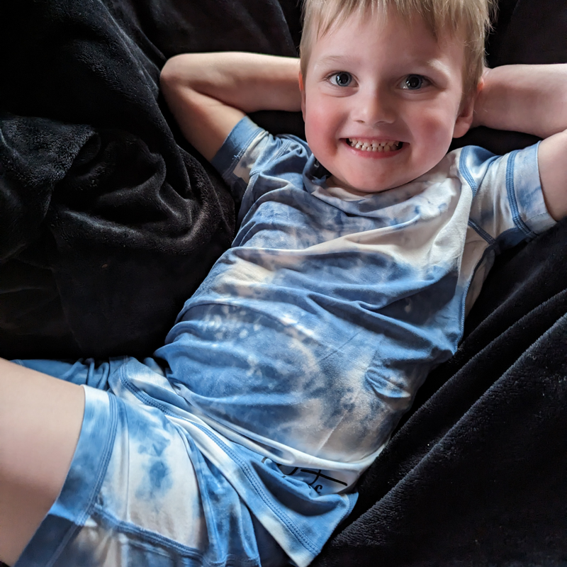 A smiling boy wearing the sea breeze short set - pajama short set - from Comfort on the Spectrum.