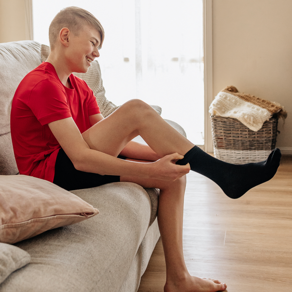 A boy trying the black soothe sensory seamless socks from Comfort on the Spectrum.