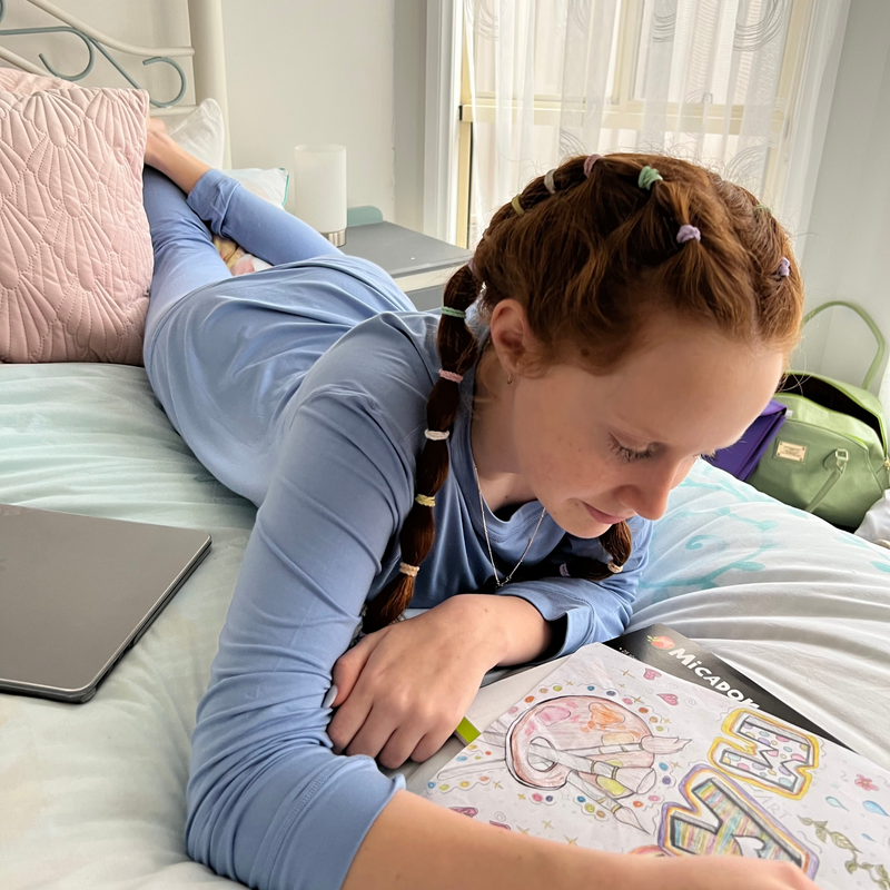 A girl in prone position wearing blueberry long set - pajama set for teens - from Comfort on the Spectrum.