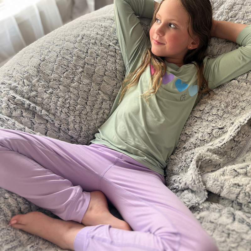 A girl wearing a Lavender Sweetheart  Long Set Pajamas for Teens & Kids from Comfort on the Spectrum.