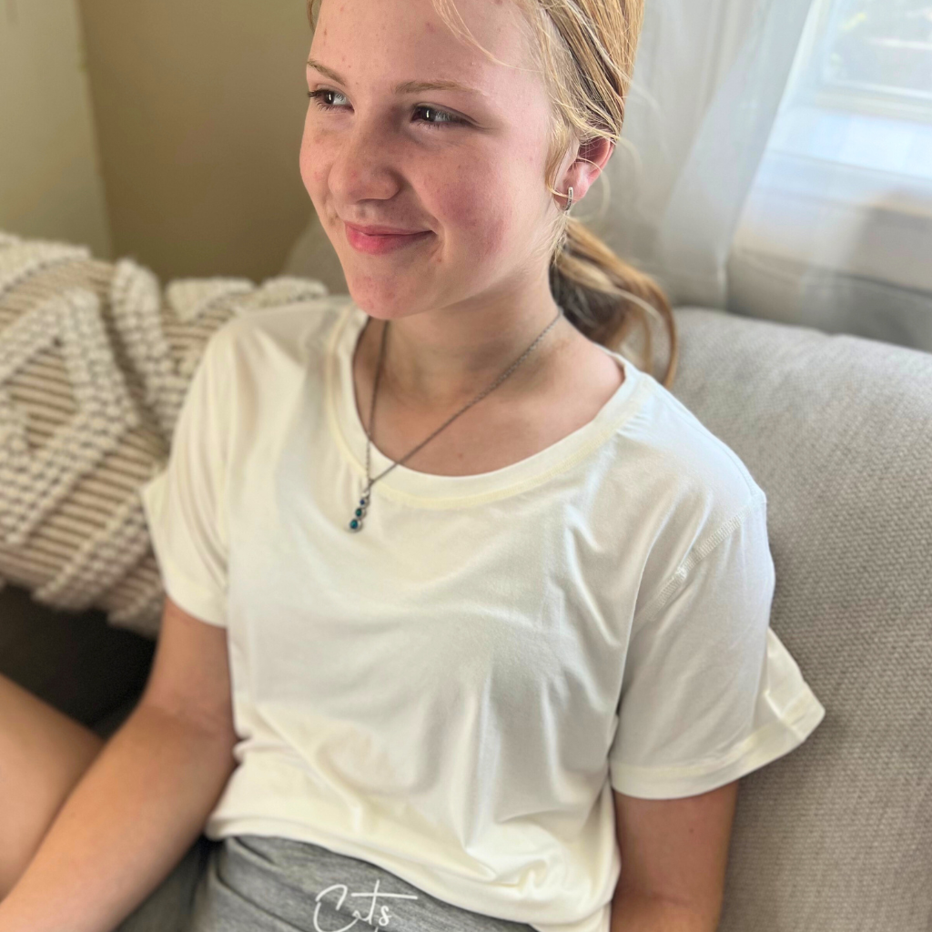 A sitting lady wearing the white bamboo t shirt and grey marle snug shorts from Comfort on the Spectrum.