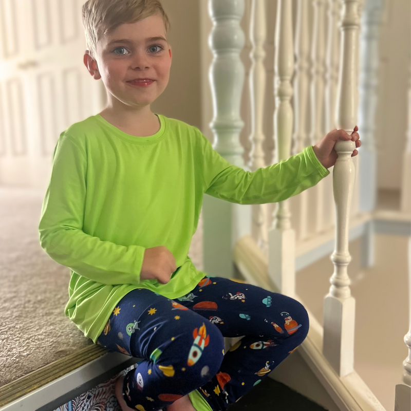 A smiling boy wearing a space invaders long set - pajamas for teens from Comfort on the Spectrum.