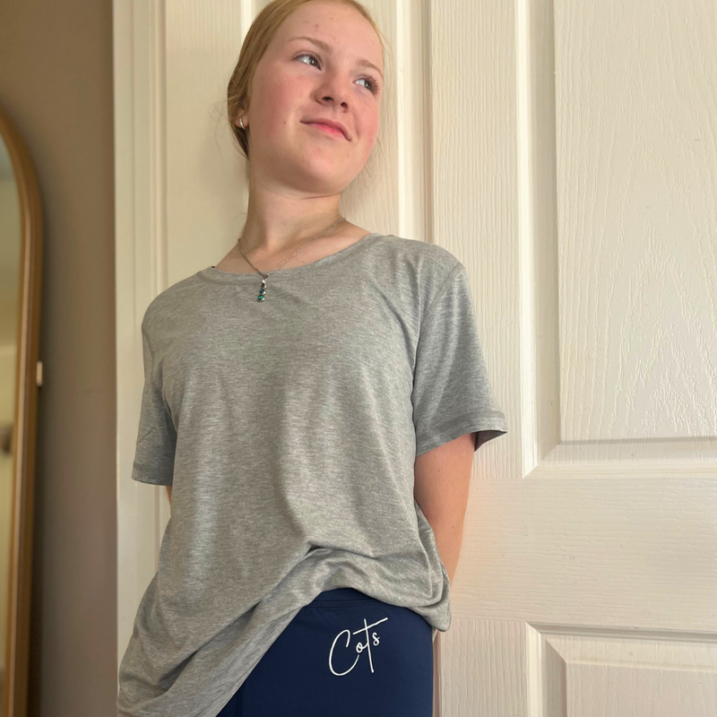 A standing girl wearing the grey marle  bamboo t shirt for adults of Comfort on the Spectrum.