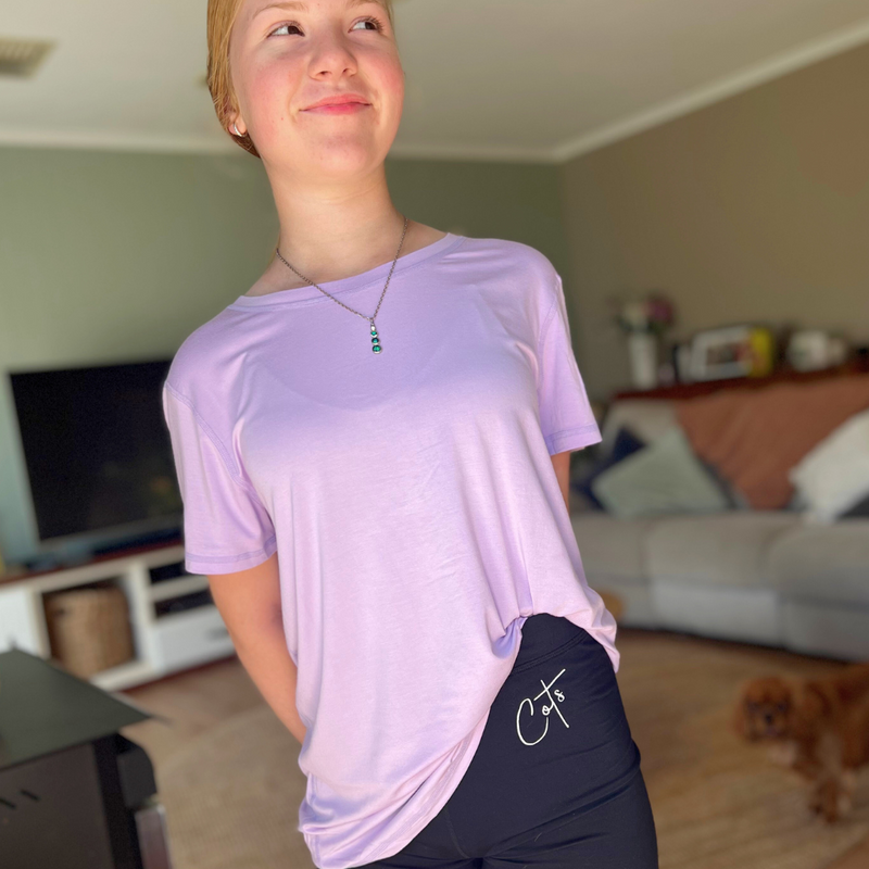 A standing girl wearing the lavender bamboo t shirt from Comfort on the Spectrum.