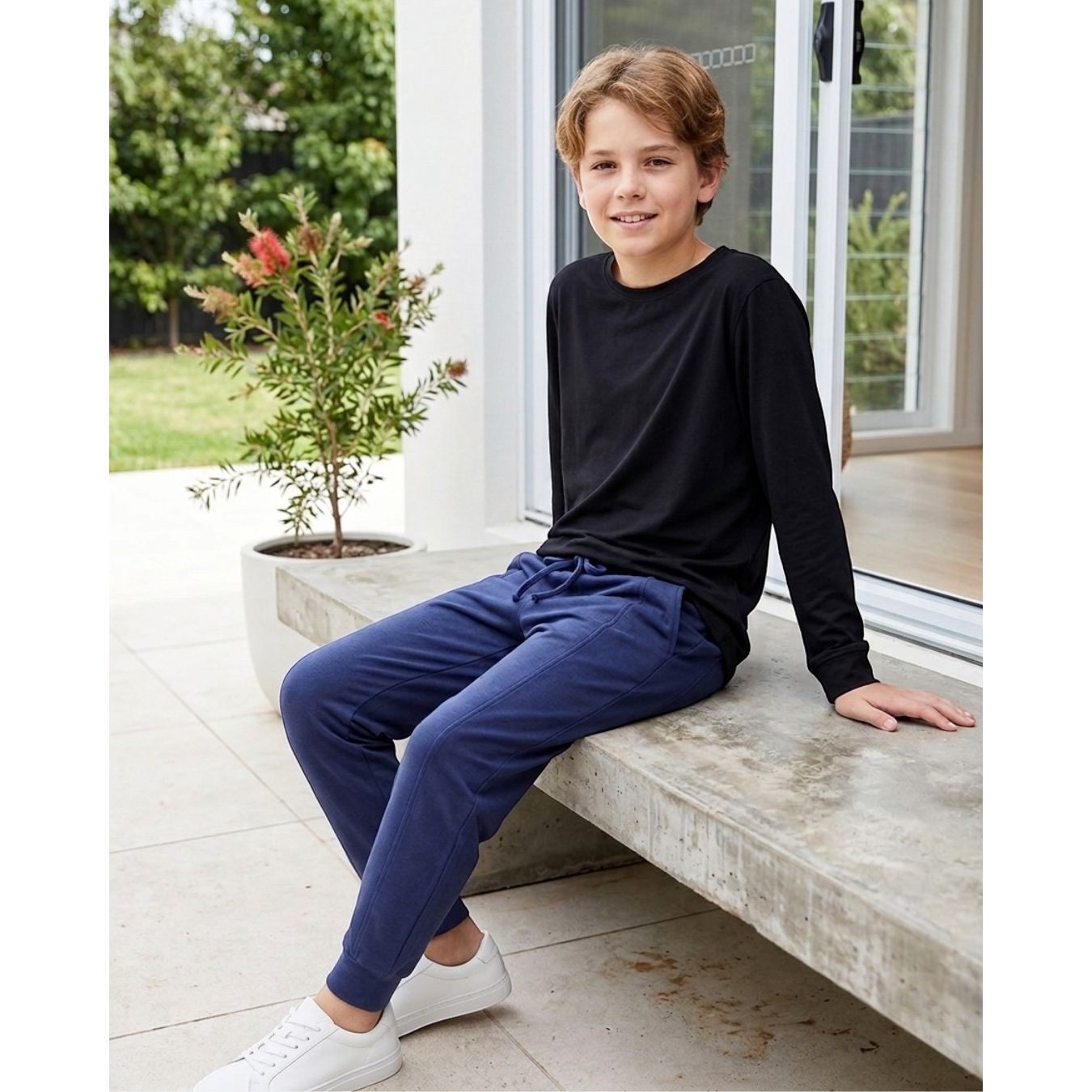 Comfort on the Spectrum navy blue bamboo/cotton blend tracksuit pants worn by a boy sitting outdoors.